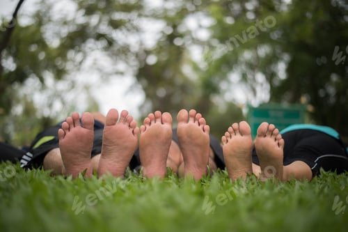 Preview: Close up of family feet togetherness on green field.