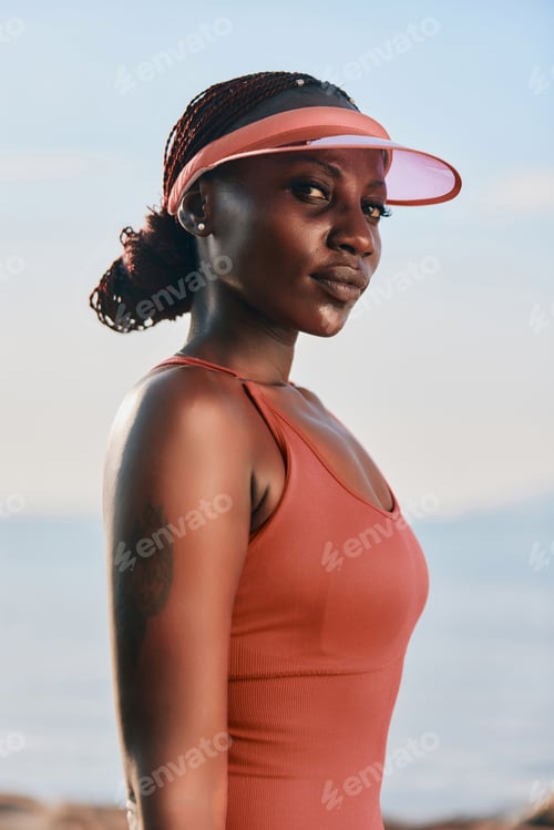 Preview: Young athlete with a stylish visor posing confidently by the beach