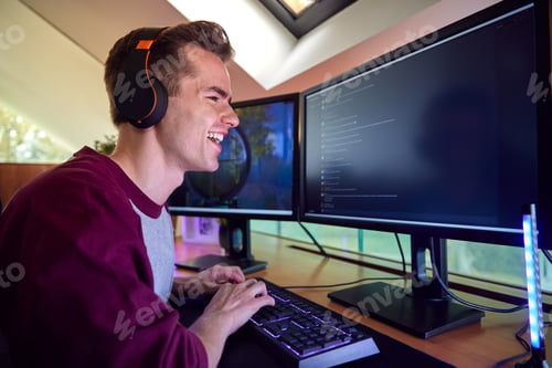 Preview: Man Gaming At Home Sitting At Desk With Multiple Monitors