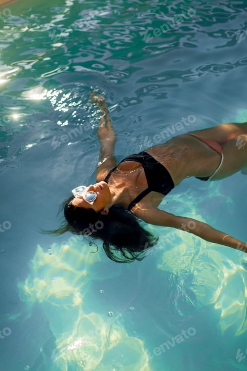 Preview: Brunette caucasian model in bikini floating in the pool water