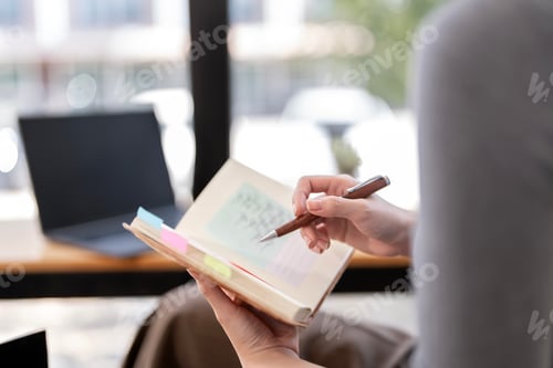 Preview: Close-up of a person's hands writing or marking in a notebook or planner during a work session.