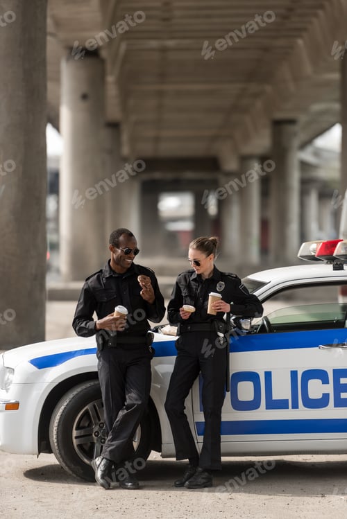Preview: police officers with coffee and doughnuts standing next to car