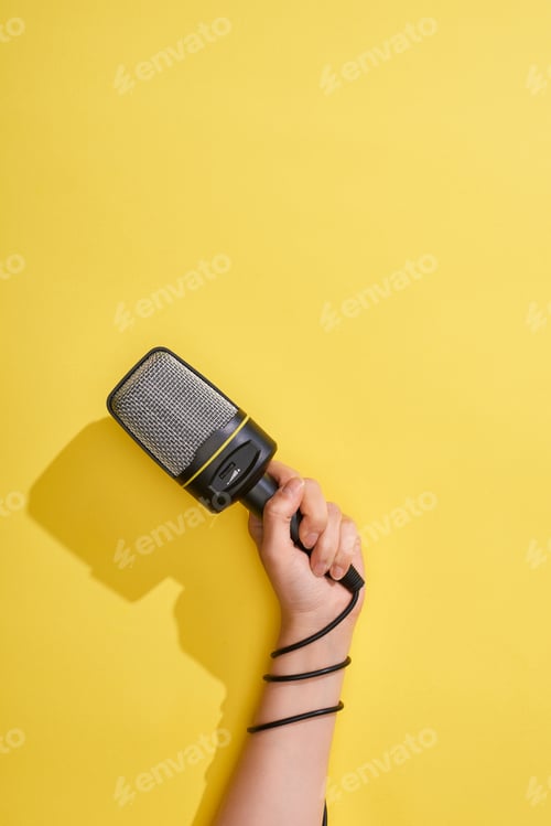 Preview: cropped view of woman holding microphone on yellow background