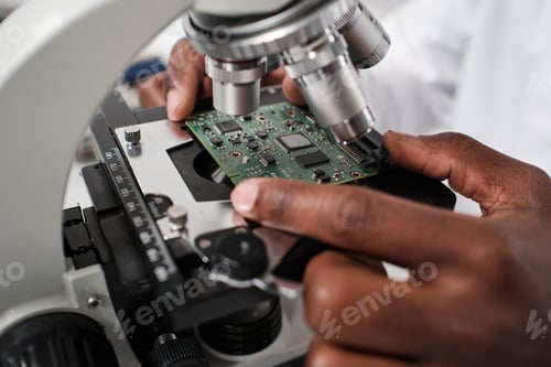 Preview: Part of hand of contemporary researcher putting circuit board in microscope