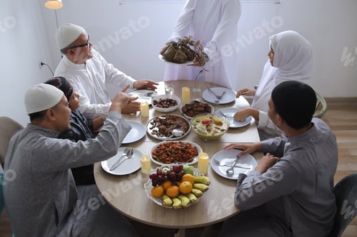 Preview: Top View Of Muslim Woman Hands Serving Ketupat On Dining Room During Eid Celebration