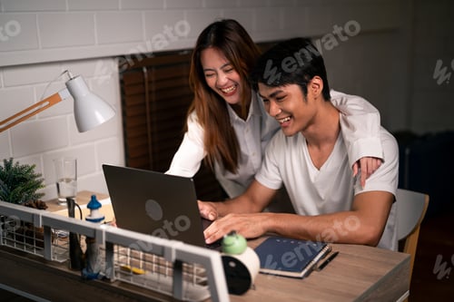 Preview: Asian young man overworking at home at night in bedroom with his wife.