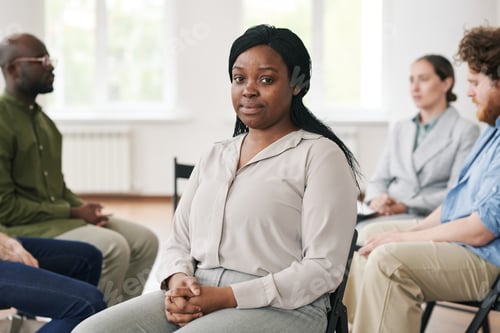 Preview: Young black woman in casual white blouse and pants sitting in front of camera