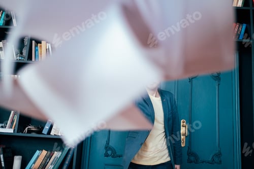 Preview: Attractive adult successful bald bearded man in suit throwing documents at camera on library book