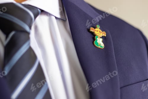 Preview: Man wearing hard rock cafe pin on suit jacket