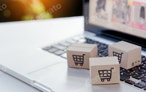 Preview: Shopping online. Cardboard box with a shopping cart logo on laptop keyboard.