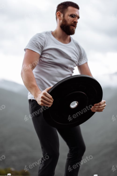 Preview: Handsome muscular hunk man looking at mountains from the peak.