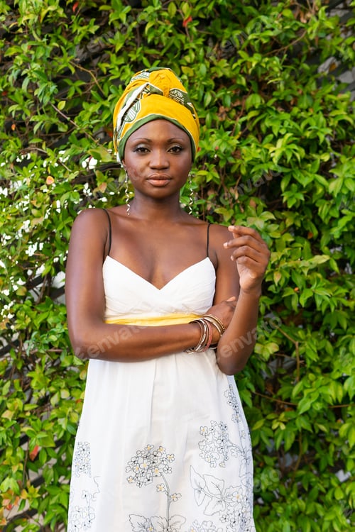 Preview: Self assured young African American female in stylish summer white dress and authentic yellow