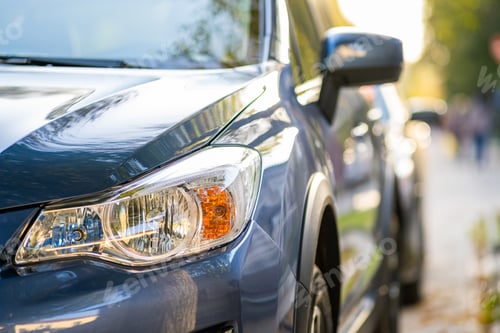 Preview: Closeup of front headlight of new clean car parked on a city street side