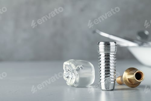 Preview: Parts of dental implant on grey table. Space for text