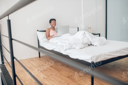 Preview: A young woman with a laptop in bed at home