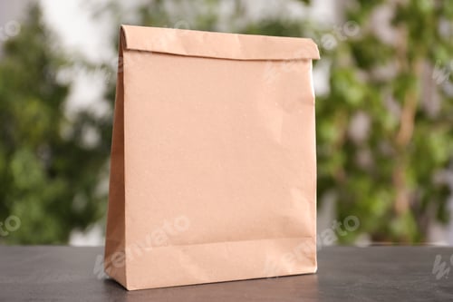 Preview: Blank paper bag on table against blurred background. Mock up for design