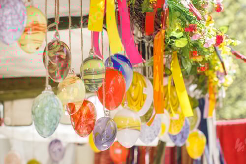 Preview: Hanging Easter Eggs with colorful stripes from the top of the wooden roof. Concept of religious