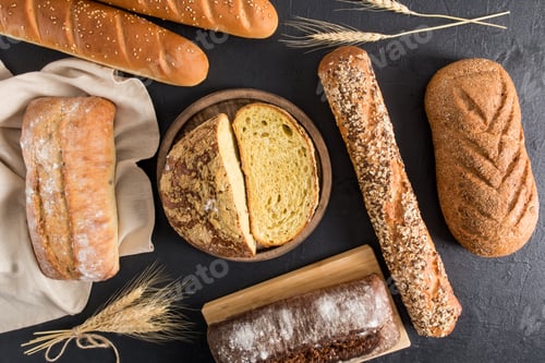 Preview: bread background. various kinds of fresh delicious bread on wooden boards and cloth towel. top view