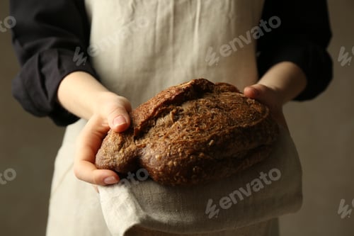 Preview: Woman with fresh loaf of bread on grey background, closeup