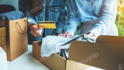 Preview: Women holding and using credit card for online shopping while opening a postal parcel box