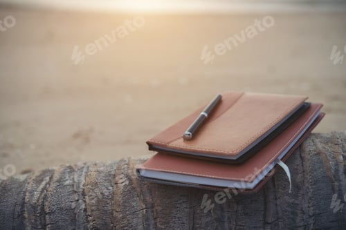 Preview: Notebooks,books and pen on the beach.