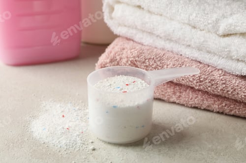 Visualização: Toalhas, líquido para roupa e colher com pó, vista de perto