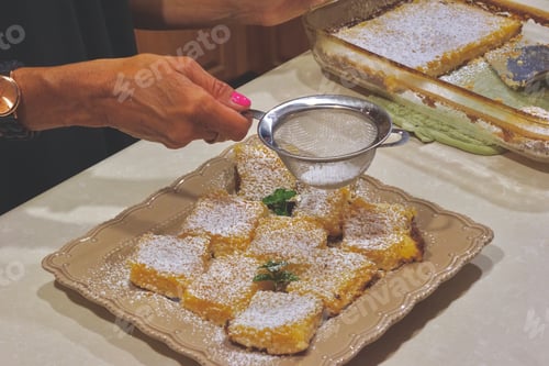 Preview: Woman putting the finishing touches on the delicious, homemade lemon squares, in the kitchen!