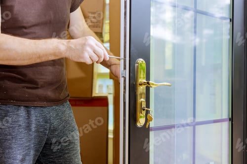 Man Fixing Door Lock with Screwdriver Indoors