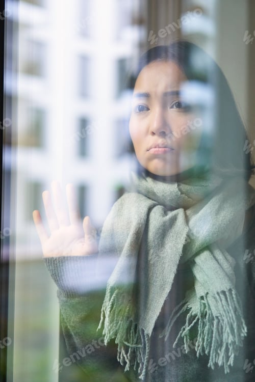 Preview: Asian woman feels unwell, stays at home, looks outside window with jealous, distressed face, wants
