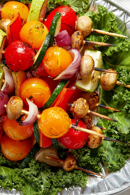 Preview: vegetarian skewers with dry herbs on wooden skewers of zucchini tomato onion mushrooms on a plate