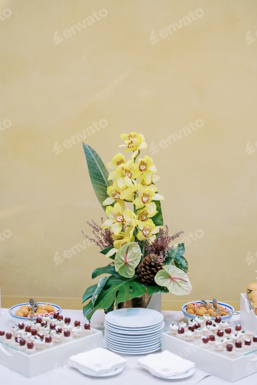 Preview: Bouquet of flowers stands on a buffet table near cupcakes on trays near the house