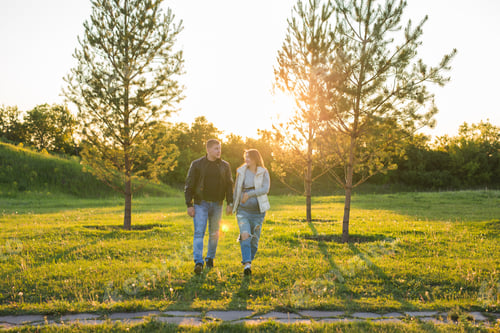 Preview: Pregnant woman with husband walking on meadow in the sunlight