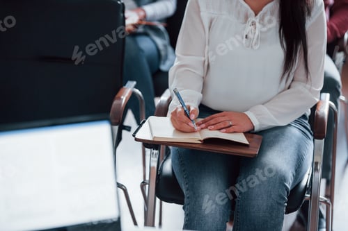 Preview: In white shirt and jeans. Group of people at business conference in modern classroom at daytime