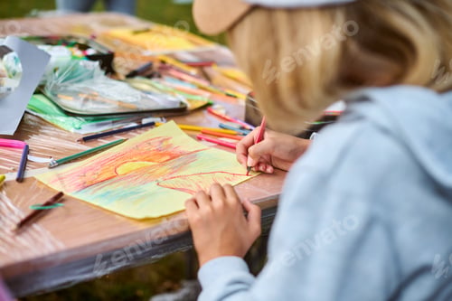 Preview: Child drawing with colors on wooden table