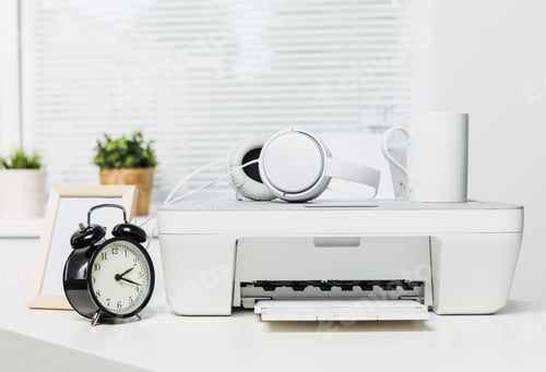 Preview: Modern workspace with printer, clock, headphones, and coffee cup captured in a bright office setting