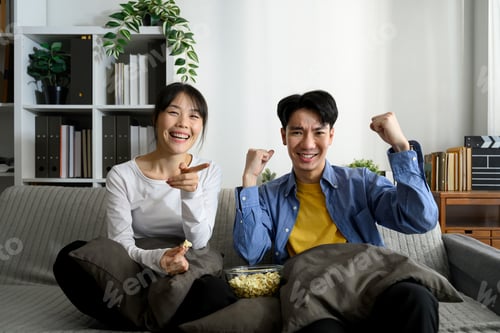 Preview: Excited couple cheering in excitement during movie night at home