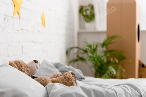 Preview: Brown teddy bear lying on bed in bedroom