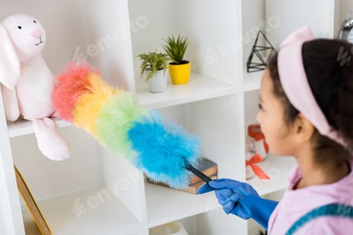 Preview: cute african american kid dusting shelving unit with multicolored duster