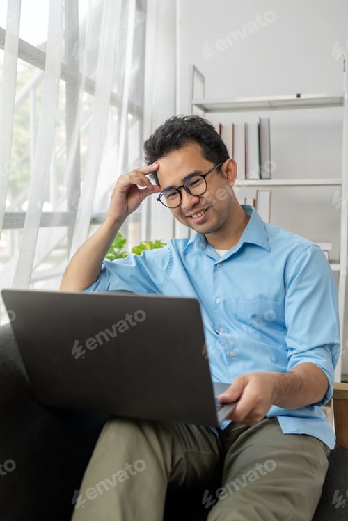 Preview: Asian man relaxing in the living room of his home, he is spending the weekend to relax, spending his