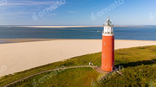 Preview: Texel Netherlands, Majestic lighthouse towering over the sandy beach on a sunny day