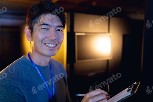 Preview: Portrait of asian male engineer smiling while writing on clipboard in computer server room