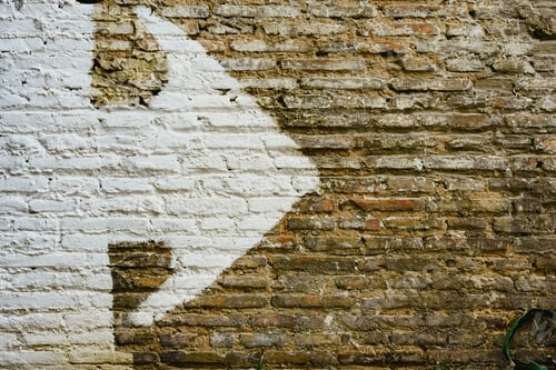 Preview: Brick wall with big white arrow indicating direction, background with copy space.