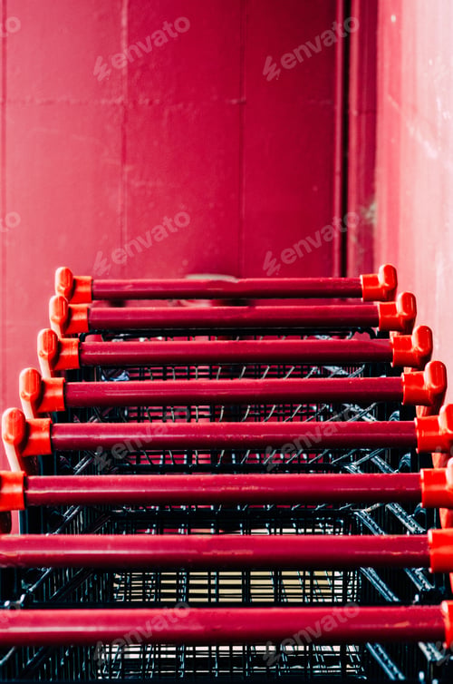 Preview: Row of shopping carts at a store near a red wall