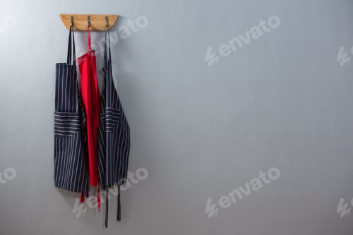 Aprons Hanging on Wooden Rack Against Gray Wall