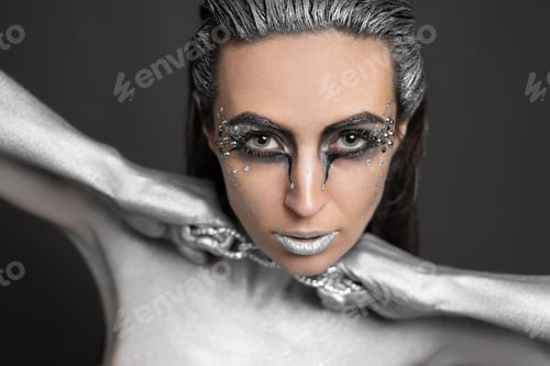 Preview: Beautiful woman with silver paint on her skin and hair breaks the chain around her neck