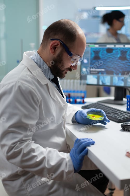 Preview: Biologist man holding medical petri dish with bacteria sample