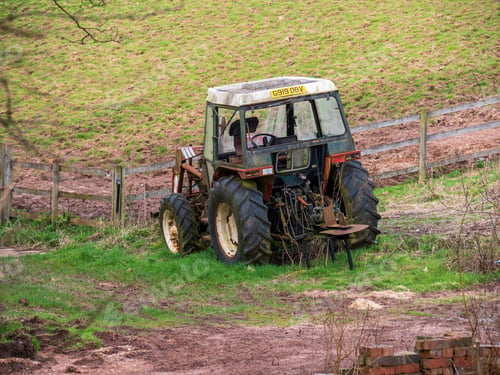 Preview: A old tractor in a filed next to a fence