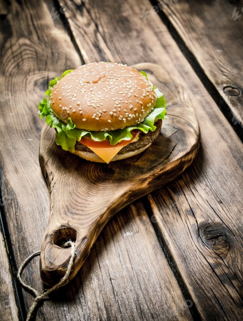 Preview: delicious Burger with meat , cheese and vegetables on wooden Board.