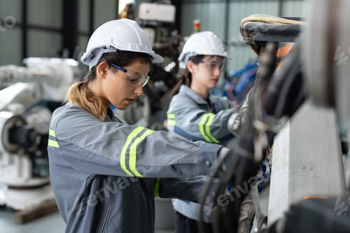Preview: Female engineer checking and maintaining robot arms machine at factory