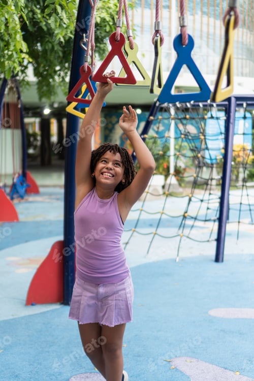 Preview: Smiling young girl playing on monkey bars children's day